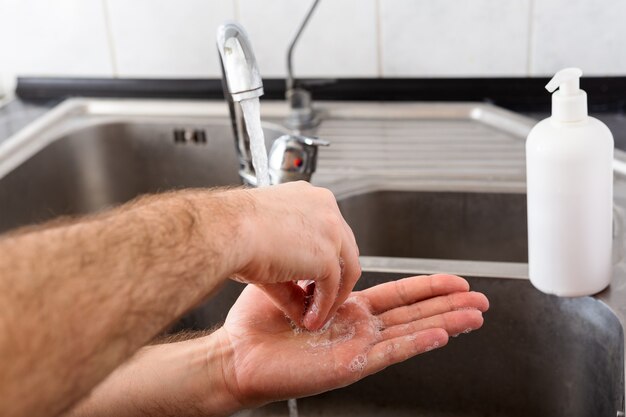Man handen wassen met antibacteriële zeep en water in metalen gootsteen