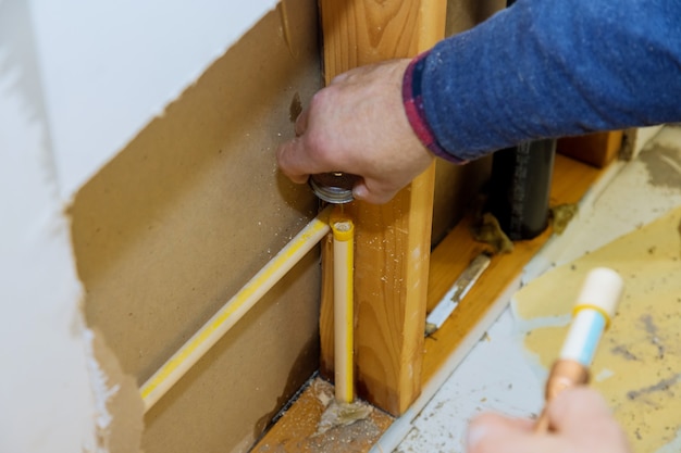 Man handleiding snijdt een stuk polypropyleen buizen af voor installatie waterleiding van een nieuw huis in aanbouw