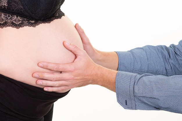 妊娠中の妻の腹に手を当てる男は、赤ちゃんが動くのを聞きます