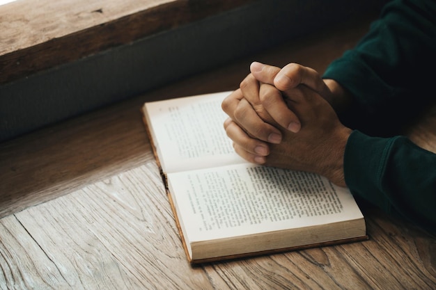 Foto mani dell'uomo giunte insieme sulla sacra bibbia nel concetto di chiesa per fede, spiritualità e religione, mano dell'uomo con la preghiera della bibbia. giornata mondiale di preghiera, giornata internazionale di preghiera, speranza, riconoscenza.