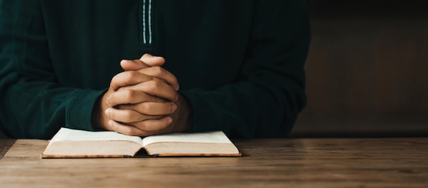 Foto mani dell'uomo giunte insieme sulla sacra bibbia nel concetto di chiesa per fede, spiritualità e religione, mano dell'uomo con la preghiera della bibbia. giornata mondiale di preghiera, giornata internazionale di preghiera, spazio per il testo.