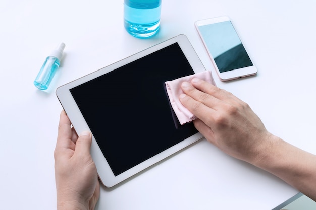 Man hands cleaning tablet with microfiber fabric and alcohol spray