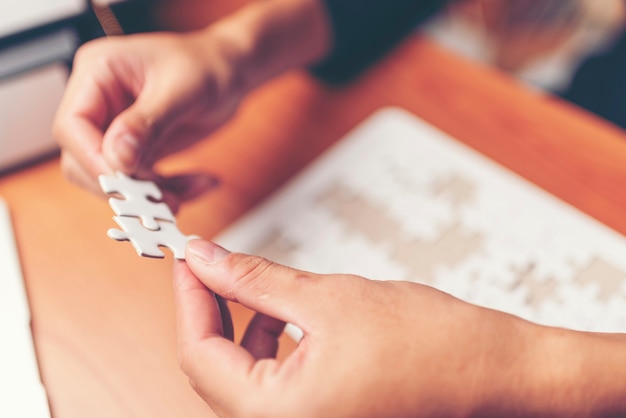 Man hands connecting couple puzzle piece in office. Business successful