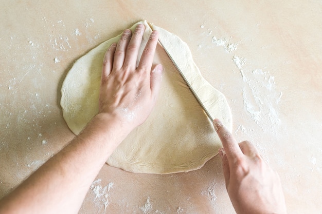 Mani dell'uomo che tagliano pasta cruda