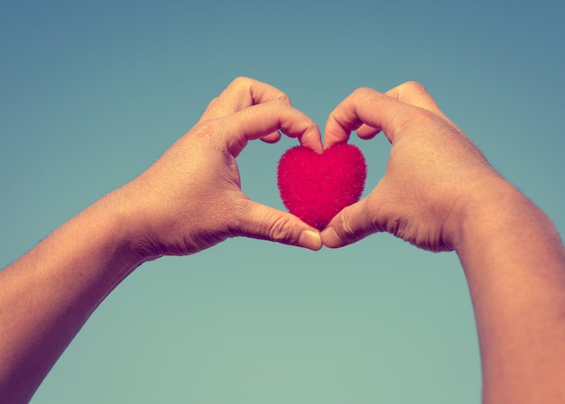 Photo man hands forming a heart showing a heart-shaped of red (love and valentine concept ), vintage color tone