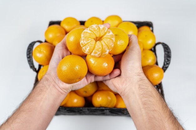 Человек руки, держа свежие и вкусные мандарины на изолированном белом фоне.