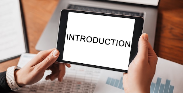 Man hands holding tablet with text Introduction at workplace