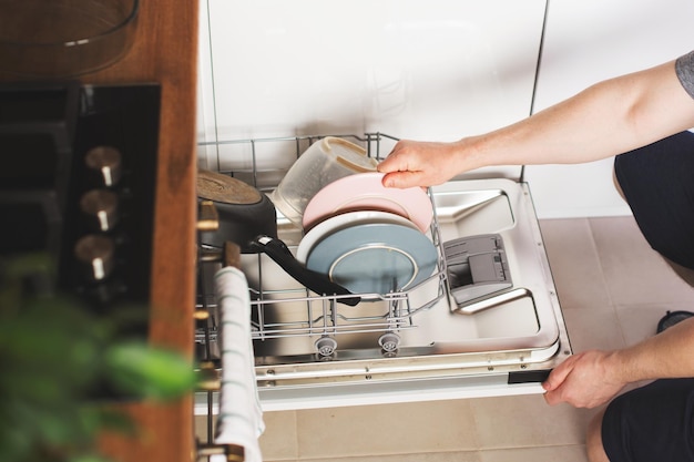 Man hands loading the dishwasher close up man chores and hosework concept