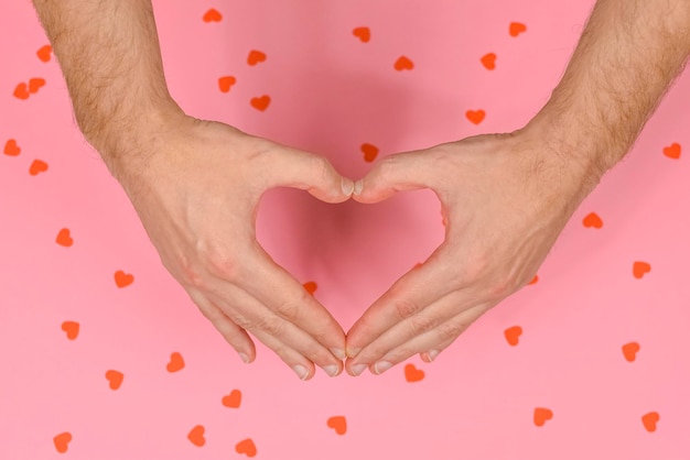 Man hands making a heart on pink background