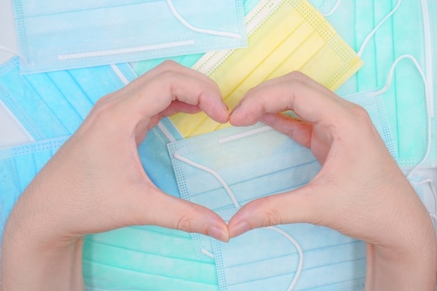 Man hands making a heart shape on Medical face masks background