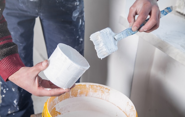 Man hands paintbrush with white paint. Renovation