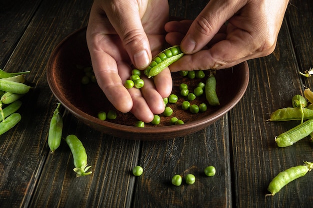 Man hands separate peas from green pods after harvest Preparation for cooking vegetarian food on the kitchen table