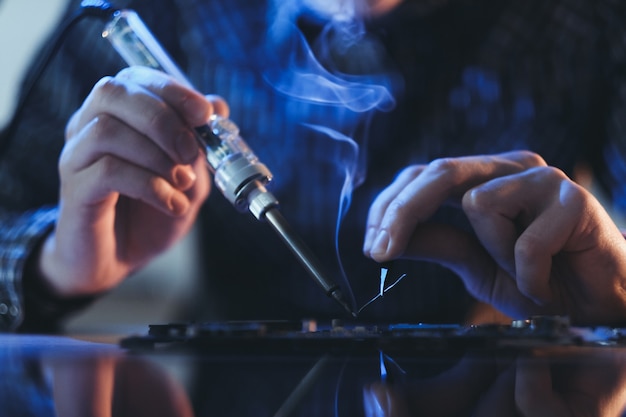 Man hands soldering electronic components on pc board