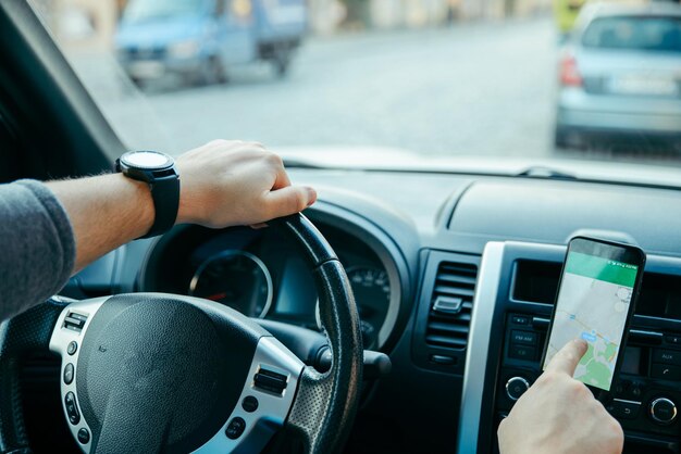 Man hands on steering wheel using phone as navigator. road trip