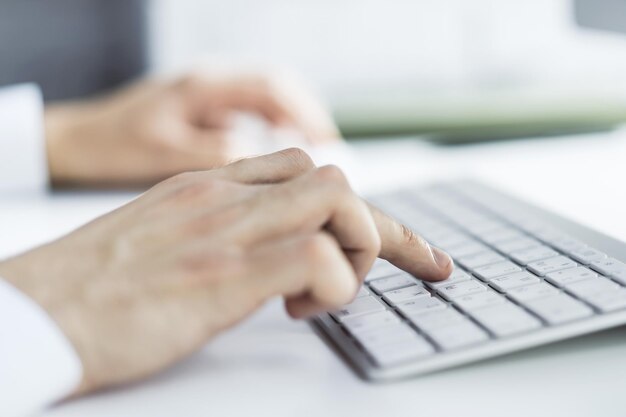 Man hands typing on computer keyboard in sunny office business and technology concept Close up