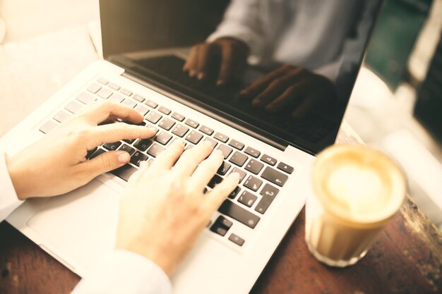 Man hands typing in laptop and cup of coffee on wooden table