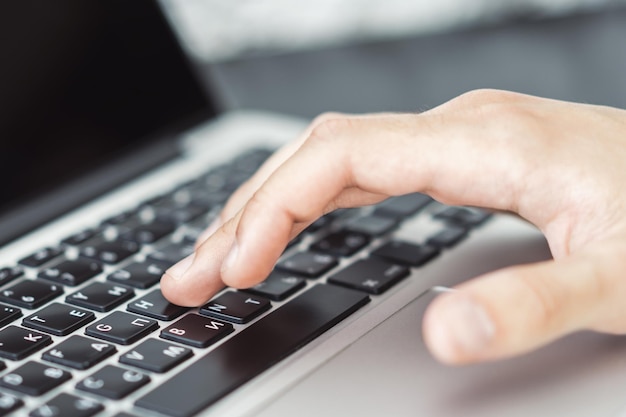 Man hands typing on laptop keyboard in sunny office business and technology concept Close up