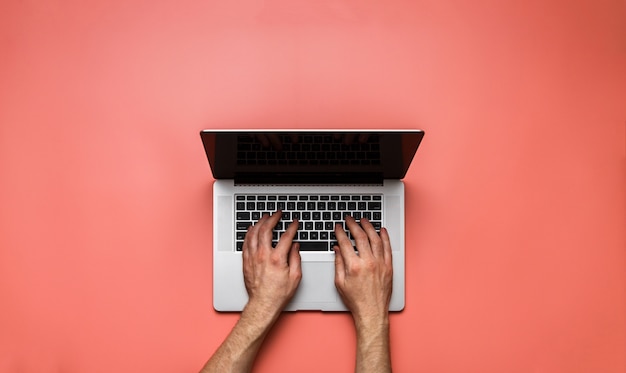 Man hands using laptop on pink desk