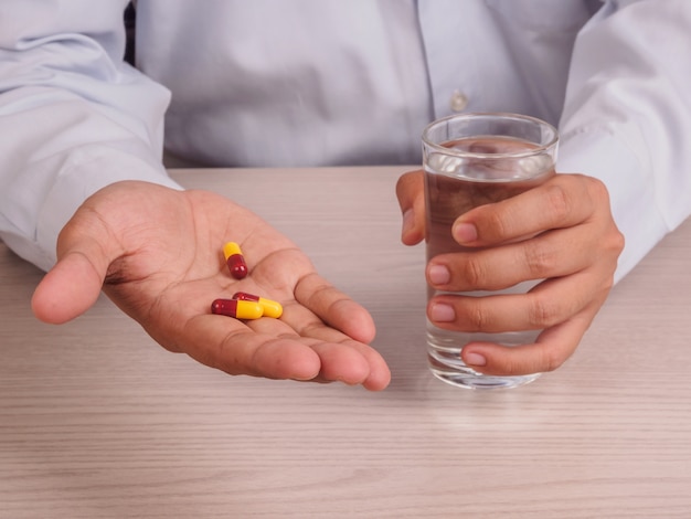 man hands with pills and glass of water