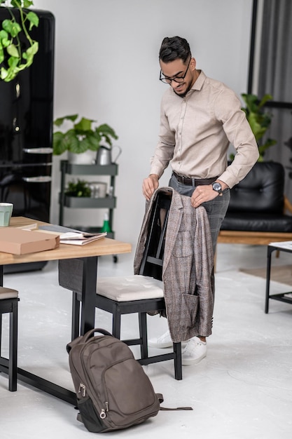 Man hanging jacket on back of chair