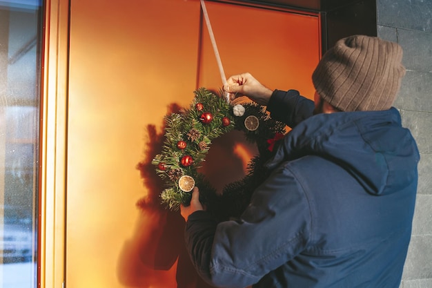 Man hangt de kerstkrans op