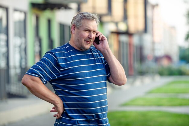 通りを歩きながらスマートフォンで楽しく話している男