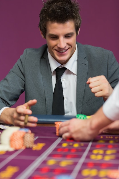 Foto uomo felice con le sue vincite al tavolo della roulette