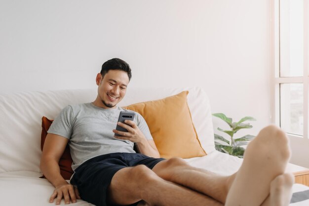 Man happy with the mobile application while relax on his sofa