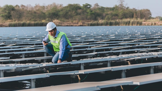 A man in a hard hat looks at a cell phone while standing on a dock.