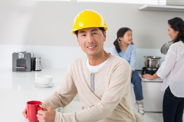 Man in hard hat with family in background at home