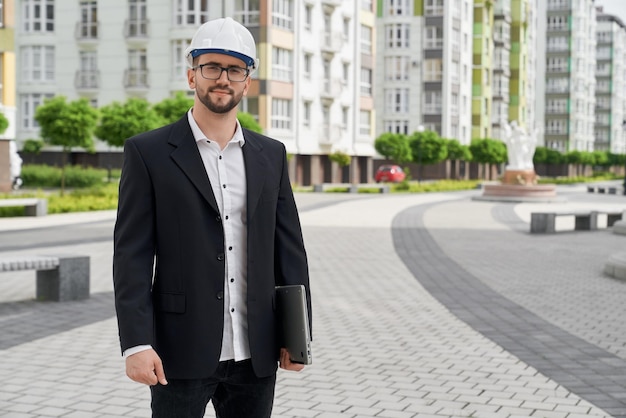 Man in hardhat standing on background of multistory houses