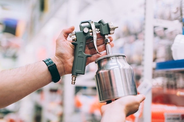 Photo a man in a hardware store holds a spray gun for painting a car.