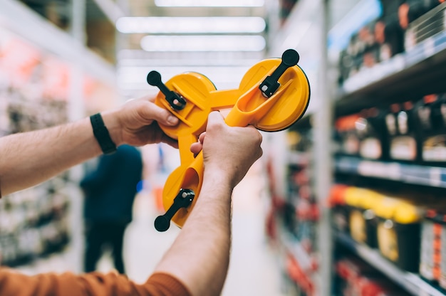 Photo a man in a hardware store holds a tool for removing and transporting mirrors and glass.