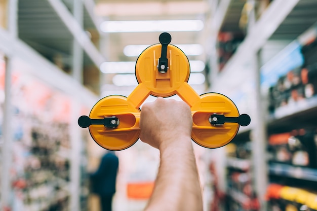 A man in a hardware store holds a tool for removing and transporting mirrors and glass.