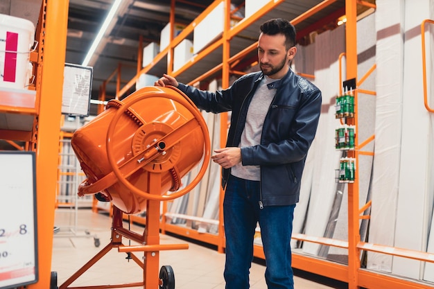 A man in a hardware store inspecting a concrete mixer