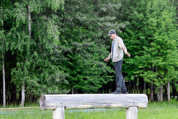 公園で楽しくバランスを取りながら丸太の上を歩く男性