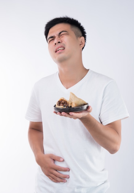 A man has a stomachache after eating delicious zongzi(rice dumpling) on Dragon Boat Festival, Asian traditional food, white background