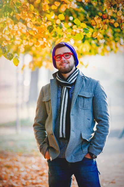 Man in hat and glasses on autumn season alley