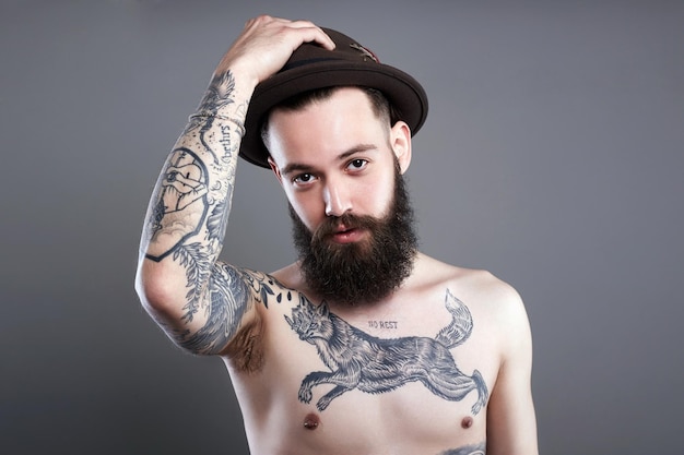 Мужчина в шляпе Мальчик-хипстер с татуировкой