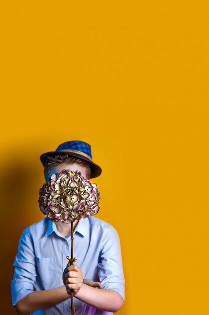 Man in a hat holding a bouquet in front of his face 