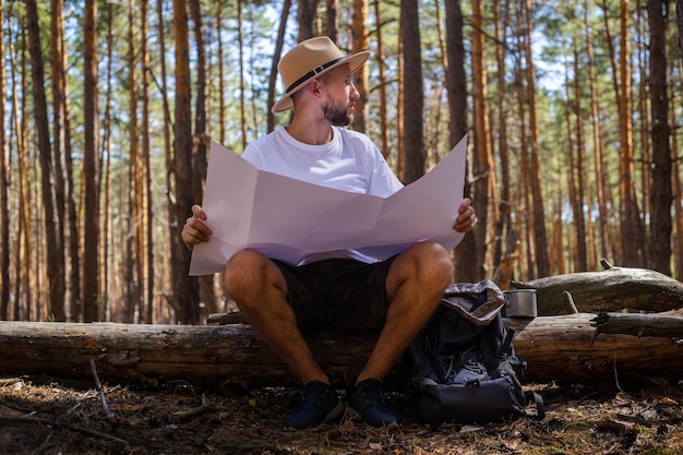 Man in a hat holds a map in his hands during a camping trip Hike in the mountains forest