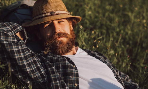 Photo man in hat lying on grass during trip in nature