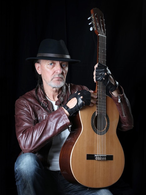 A man in a hat and with a guitar on a black background