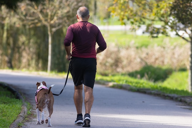 Foto un uomo fa jogging nel parco con un cane al guinzaglio