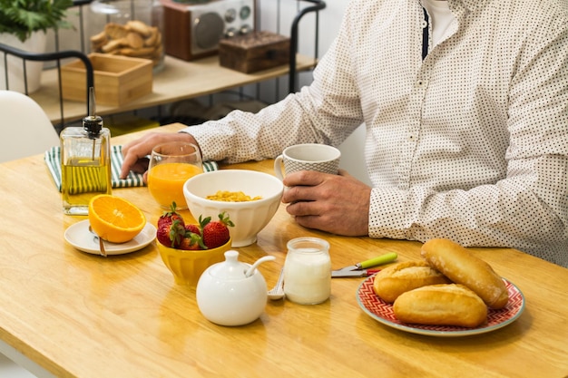 一杯のコーヒーとオレンジジュースで朝食を食べている男