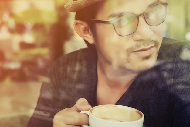 Foto uomo che beve caffè visto attraverso il vetro