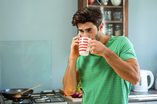 キッチンで電話で話しながらコーヒーを飲んでいる人