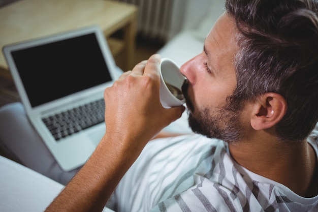 Man having coffee while using laptop