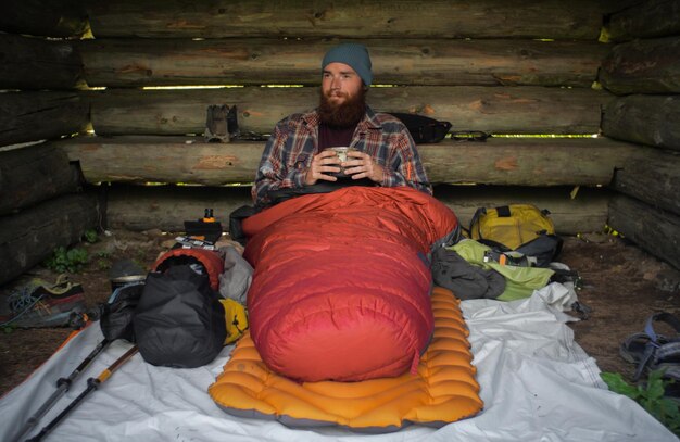 Photo man having drink while sitting in log cabin