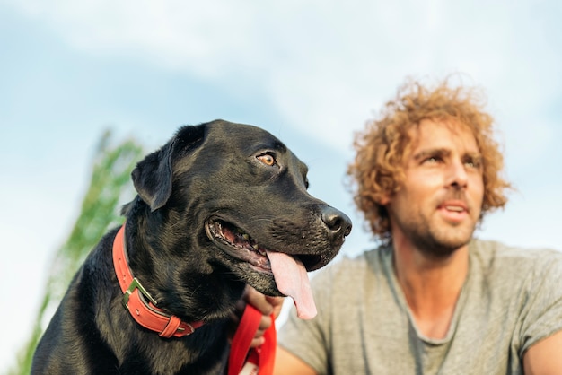 写真 公園で犬と遊んで楽しんでいる男。